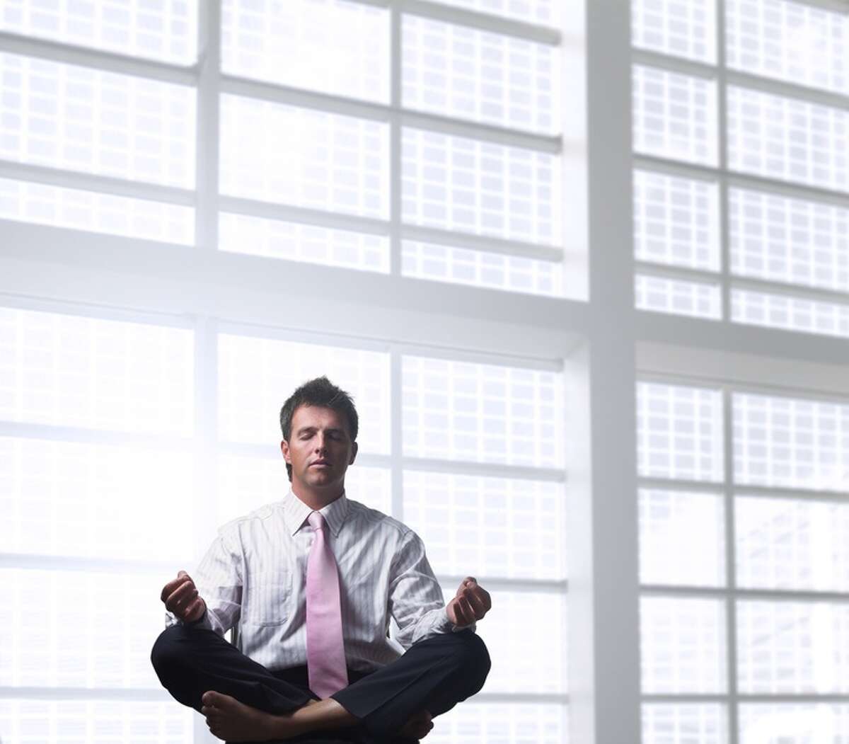 Handsome businessman is relaxing in the office, sitting in a traditional yoga lotus position. meditation FOTOLIA