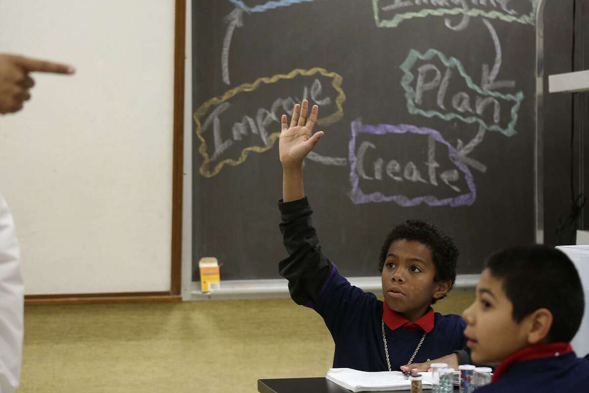 Treyvon Martinez raises his hand to answer a question in his class during Engineering Friday at Bowden Elementary Schoo.l in December. Christian Salazar, right, looks on as their class of fifth-graders learn about submersion science. Visitors could hear the proverbial pin drop, students were so engaged.