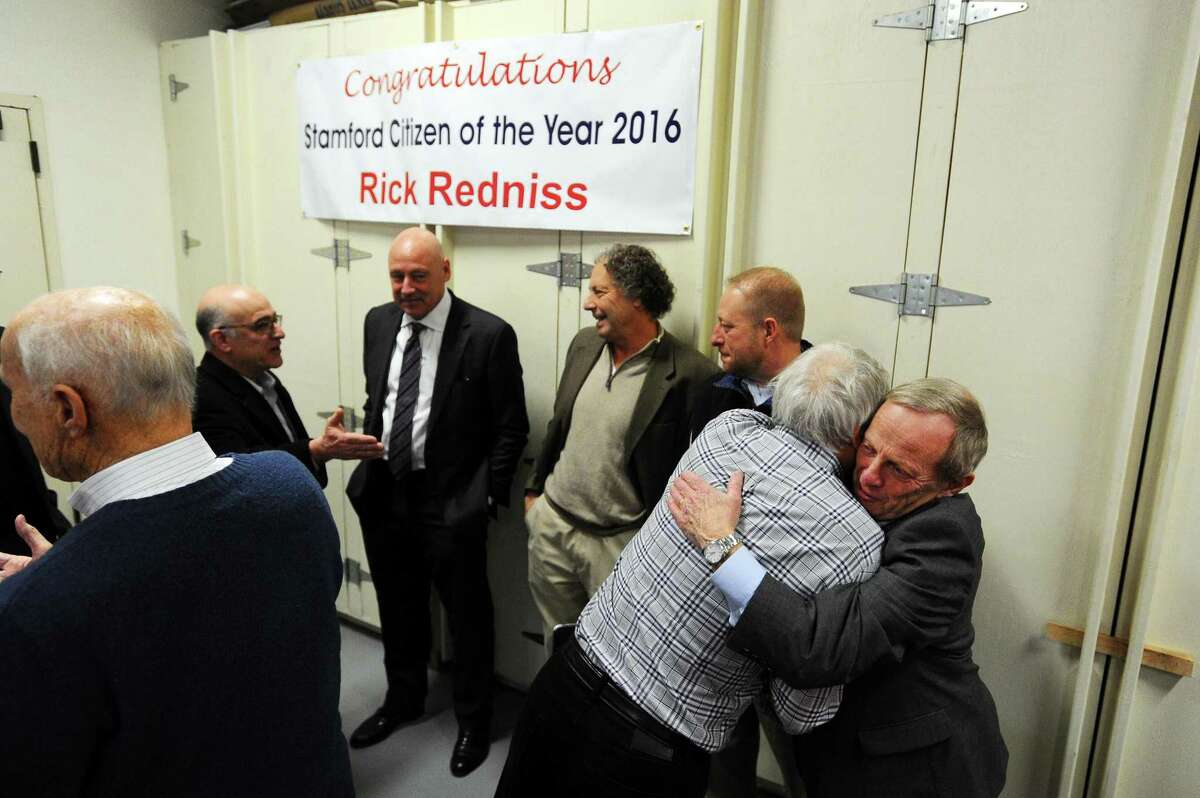 2016 Stamford Citizen of the Year Rick Redniss hugs a friend after being surprised with the honor in the garage behind his office on First St. in Stamford, Conn. on Wednesday, Dec. 21, 2016.
