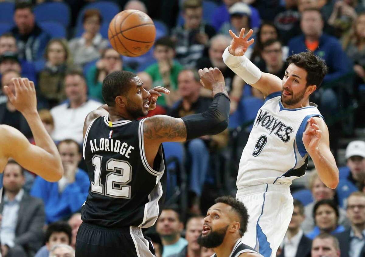 Minnesota Timberwolves' Ricky Rubio, right, of Spain, sends a pass over San Antonio Spurs' LaMarcus Aldridge during the first half of an NBA basketball game Tuesday, March 21, 2017, in Minneapolis. (AP Photo/Jim Mone)