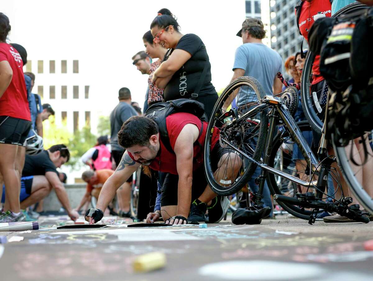 Anthony Alaniz, center in red, adds his name to a symbolic bike lane during a rally for the Houston Bike Plan at Houston City Hall on March 21.