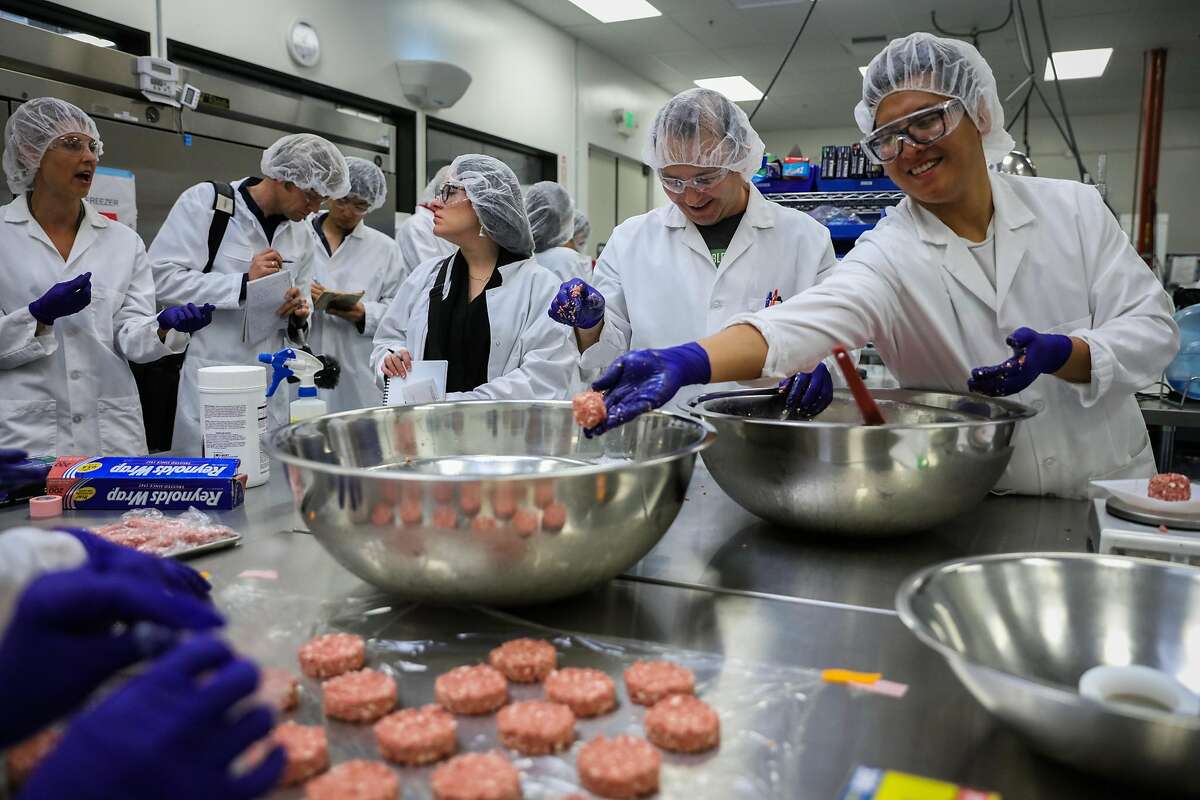 Kevin Hong (right) throws a ball of plant based meat into a bowl, while preparing food in the test kitchen at the Impossible Foods headquarters in Redwood City, California, on Thursday, Oct. 6, 2016.