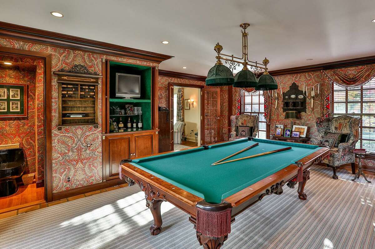The billiard room has a terra cotta tile floor and French doors to yet another patio, this one with a tall stone wall that creates a courtyard with a lion fountain.
