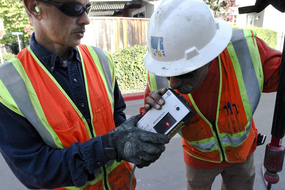 PG&E Representative Mike Jacobs, left, has Equipment Operator Mike Arreola smell a gas detector for any traces of natural gas as PG&E performs inspections of underground gas lines surrounding the home that was destoryed by a fire caused by a gas leak the night before on Thursday, September 1, 2011 in Cupertino, Calif.