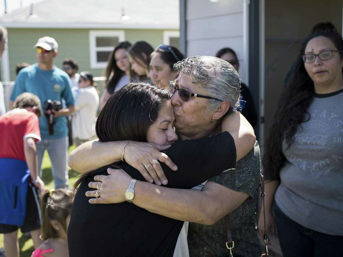 Reyna Guevara, left, hugs her mother Antonia Guevara, center right, as they tour the daughter's new home together for the first time during Habitat for Humanity's dedication of 14 new homes and of their 1000th home in San Antonio on Saturday, March 25, 2017 in San Antonio, Texas. The Guevara's home is the 1000th home to be built in San Antonio.