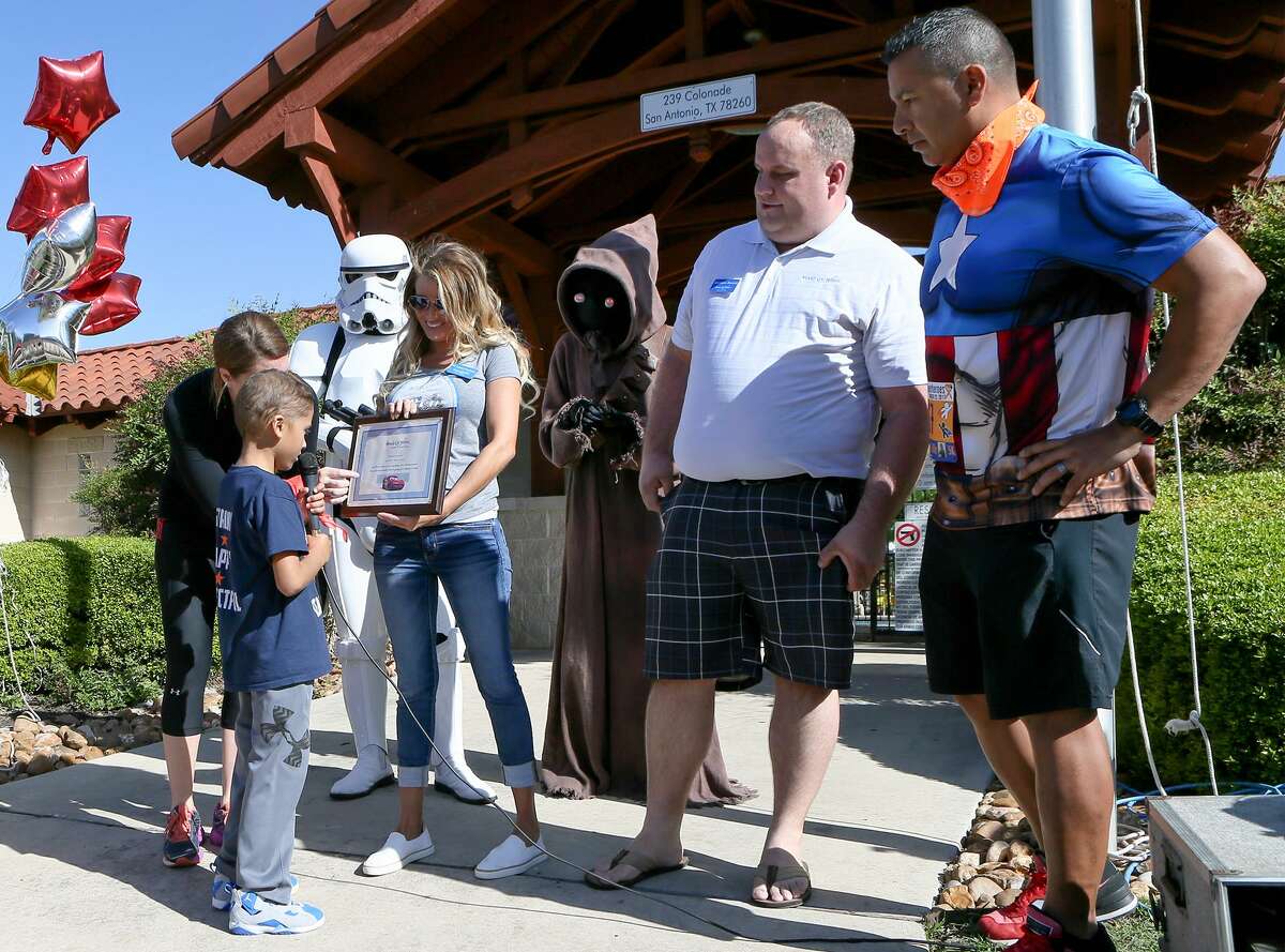 Mason "Ace" Martinez, 8, reads a plaque held by Kristen Atchley with the Make-A-Wish Foundation saying that he and his family will be going on a Disney cruise during the Mason's Mighty Superhero Run at 239 Colonade Dr in Stone Oak Heights on Saturday, March 25,2017. Mason, who has been diagnosed with Acute Lymphocytic Leukemia, had decided to raise money for someone else's wish with the fundraising event but was surprised to find he was given one too. With Mason is his mother, Stacy Martinez (from left), a Storm Trooper and Jawa ( Chris Berban and Maria Morrell), Matthew Kostak with Make-A Wish and his father Jeff Martinez. MARVIN PFEIFFER/ mpfeiffer@express-news.net