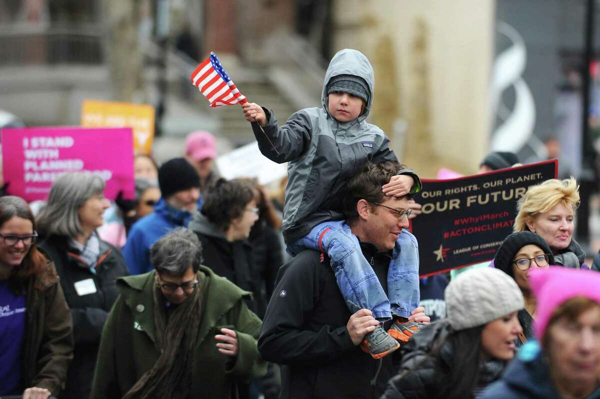 Seven-year old Andrew Meisel, of Westport, waves a flag while sitting on his father's shoulders during CT on the MOVE's "A March to Defend Democracy" in Westport, Conn. on Sunday, March 26, 2017.