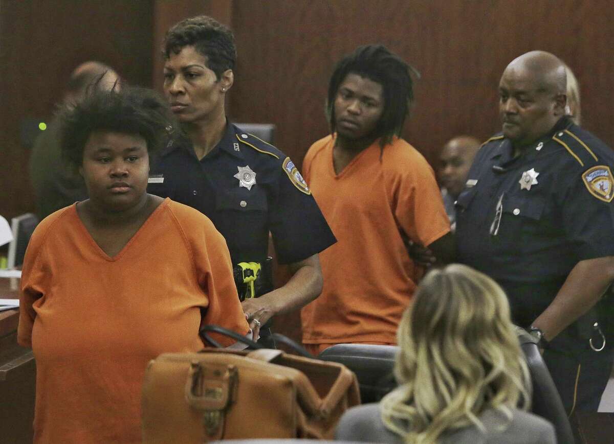 Courtney Burks, left, and her co-defendant, Shaquan Bennett, are escorted from an appearance in the Harris County 179th Criminal Court Monday, March 27, 2017. The two 18-year-olds are accused of killing a 56-year-old man, whose body was found earlier this month in a burning dumpster in east Houston. They were charged Thursday with capital murder.