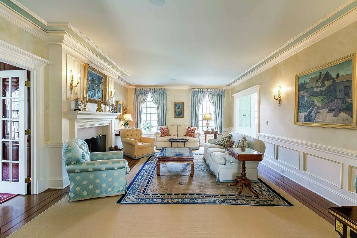 The formal living room has wainscoting on the lower walls and a marble fireplace.