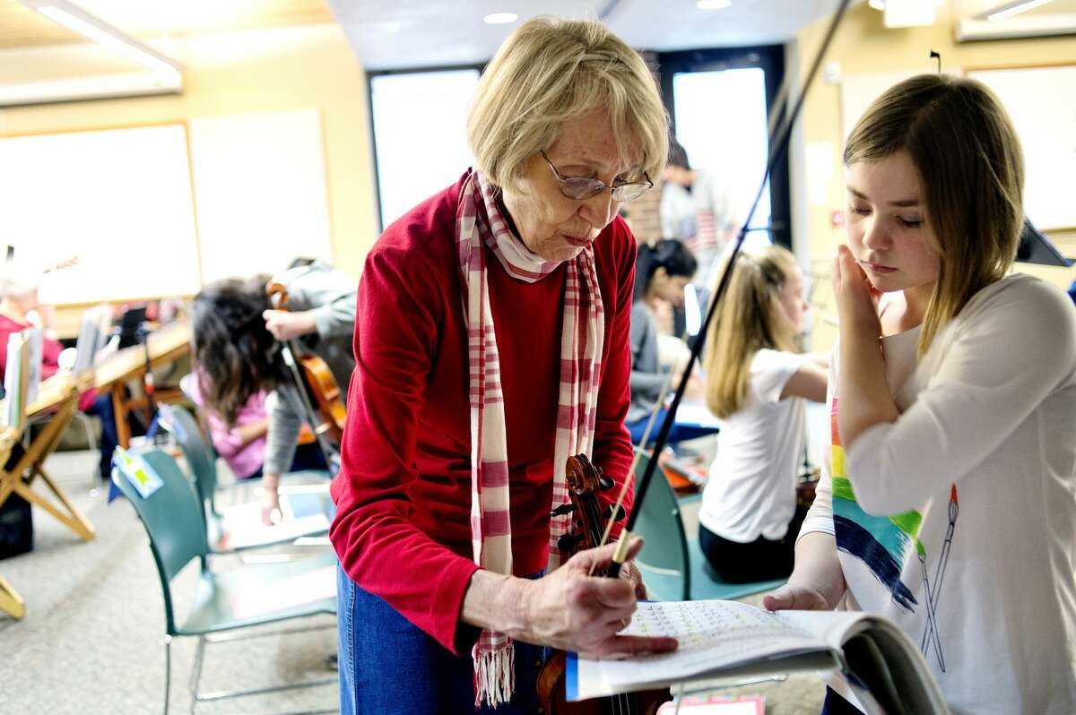 Violin instructor Janet Kroon, left, helps student Amilia Robinette before the Jolly Hammers and Strings Dulcimers concert on Saturday at the Chippewa Nature Center. The concert featured Kroon's students.