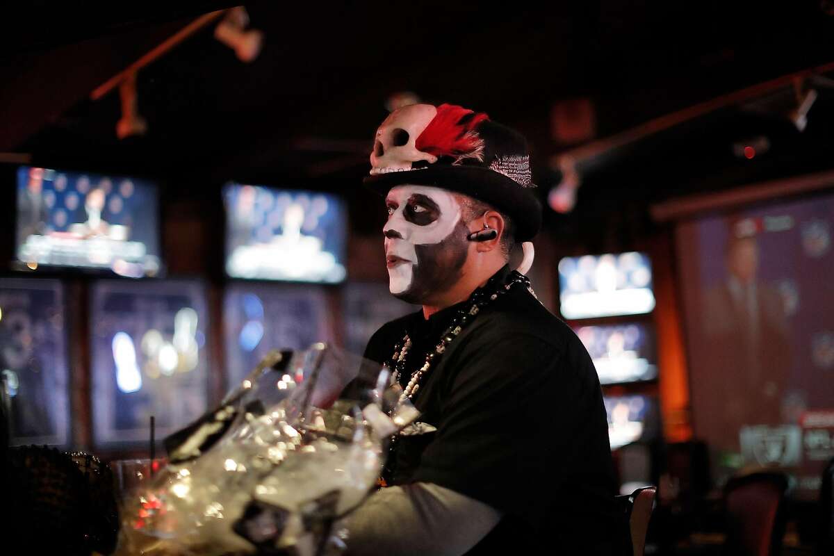 Michael Lambirth, aka VooDoo Man, is surrounded by the news of the Raiders imminent departure as it was announced on multiple screens at Ricky's Sports Theater and Grill in San Leandro, Calif., on Monday, March 27, 2017. The NFL announced that team owners had approved the Raiders' move to Las Vegas.