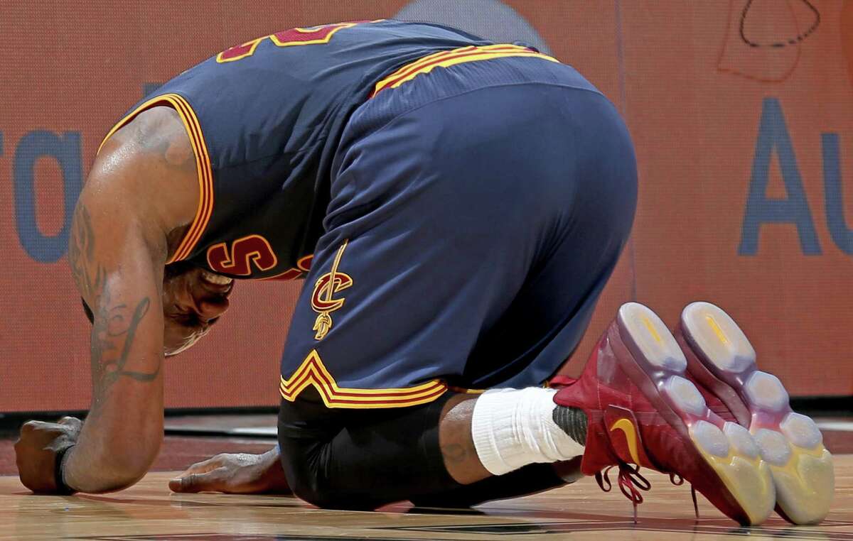 Cleveland Cavaliers' LeBron James kneels on the court after being injured on a play during second half action against the San Antonio Spurs Monday March 27, 2017 at the AT&T Center.