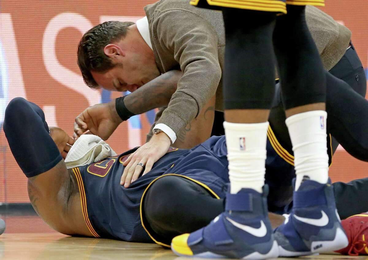 Cleveland Cavaliers' LeBron James is checked by head athletic trainer Stephen Spiro after being injured on a play during second half action against the San Antonio Spurs Monday March 27, 2017 at the AT&T Center.