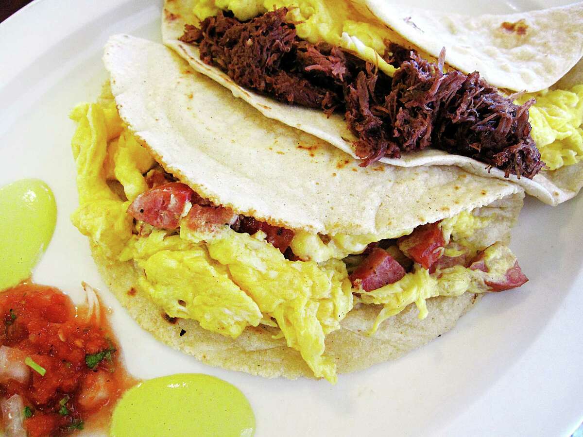 Country and egg taco on a handmade corn tortilla, foreground, and a barbacoa and egg taco on flour from Erick's Tacos.
