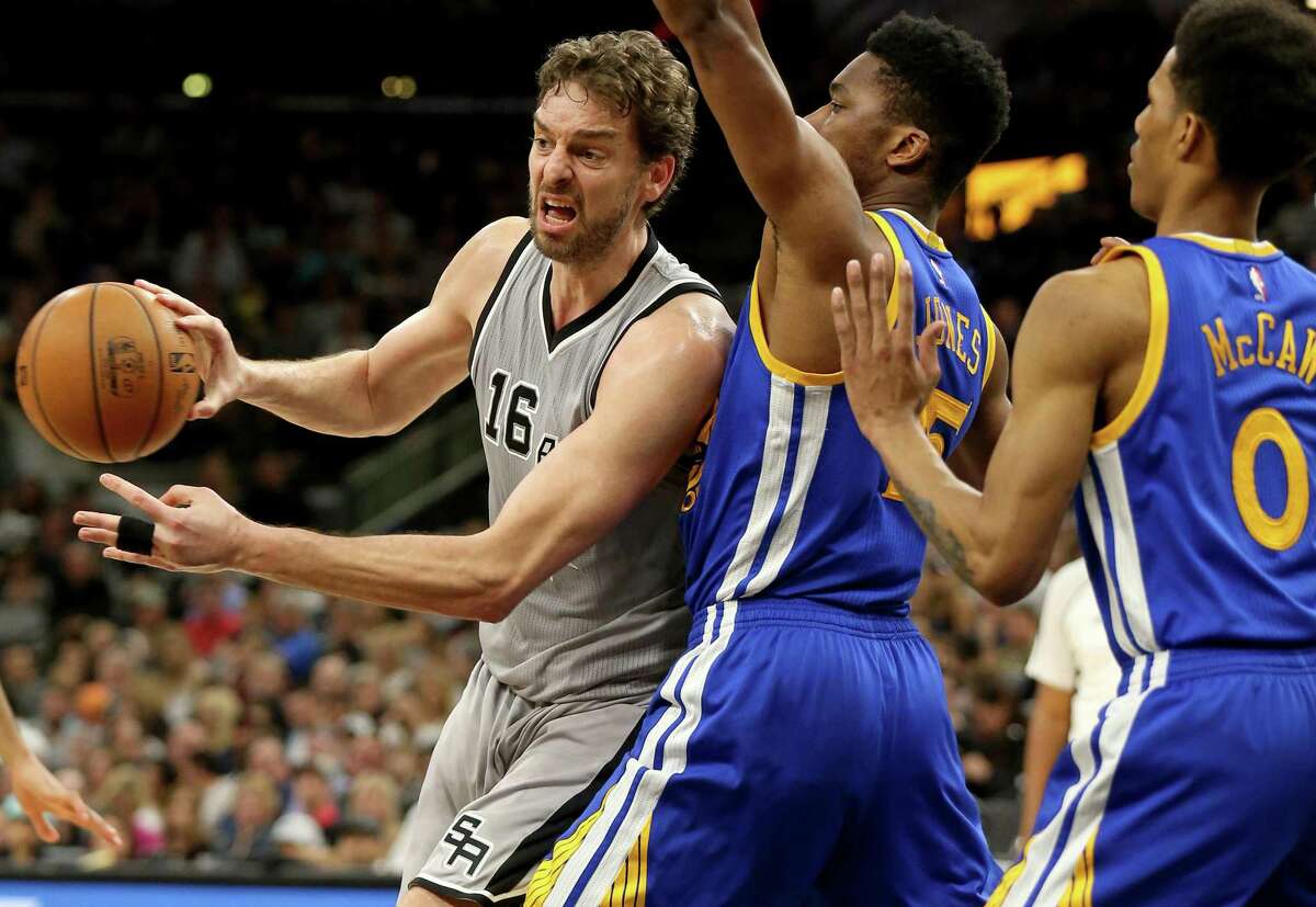 Spurs’ Pau Gasol looks to pass around the Golden State Warriors’ Kevon Looney (left) and Patrick McCaw during second half action on March 11, 2017 at the AT&T Center.