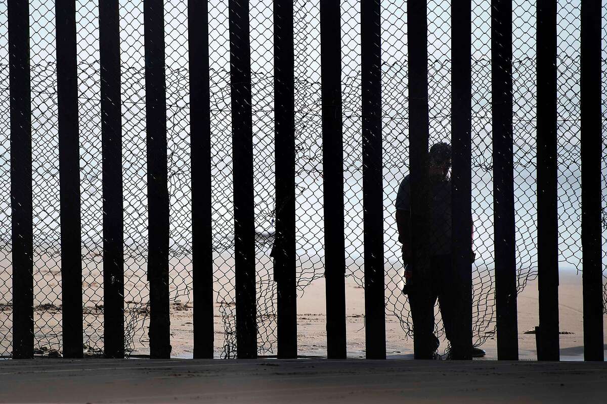 This file photo taken on February 13, 2017 shows a man standing on the Mexico side of a border fence separating the beaches at Border Field State Park, in San Diego, CA.
