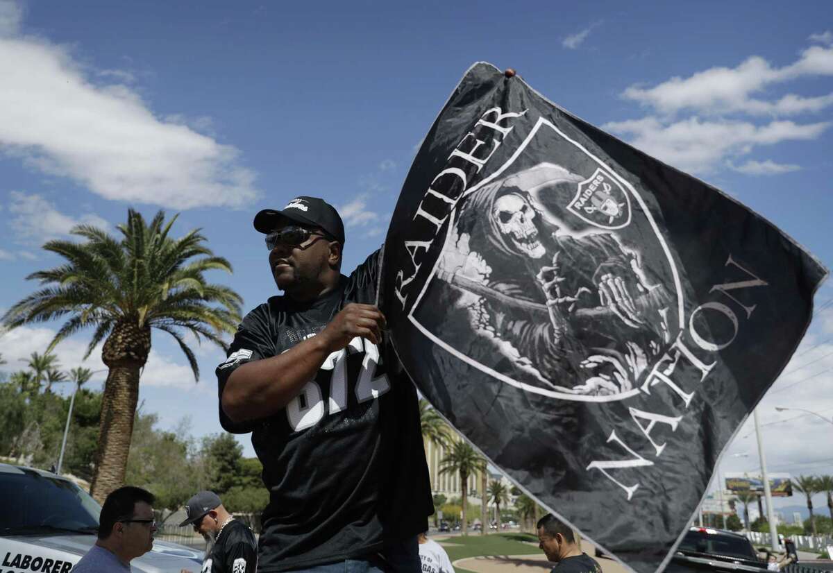 Ken Mclin holds up a Raiders banner on March 27, 2017, in Las Vegas. NFL team owners approved the move of the Raiders to Las Vegas in a vote at an NFL annual meeting in Phoenix.