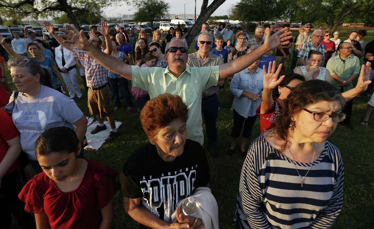 Joel McLeod extends his arms in prayer as he joins others from La Vernia at a prayer service at the city park.
