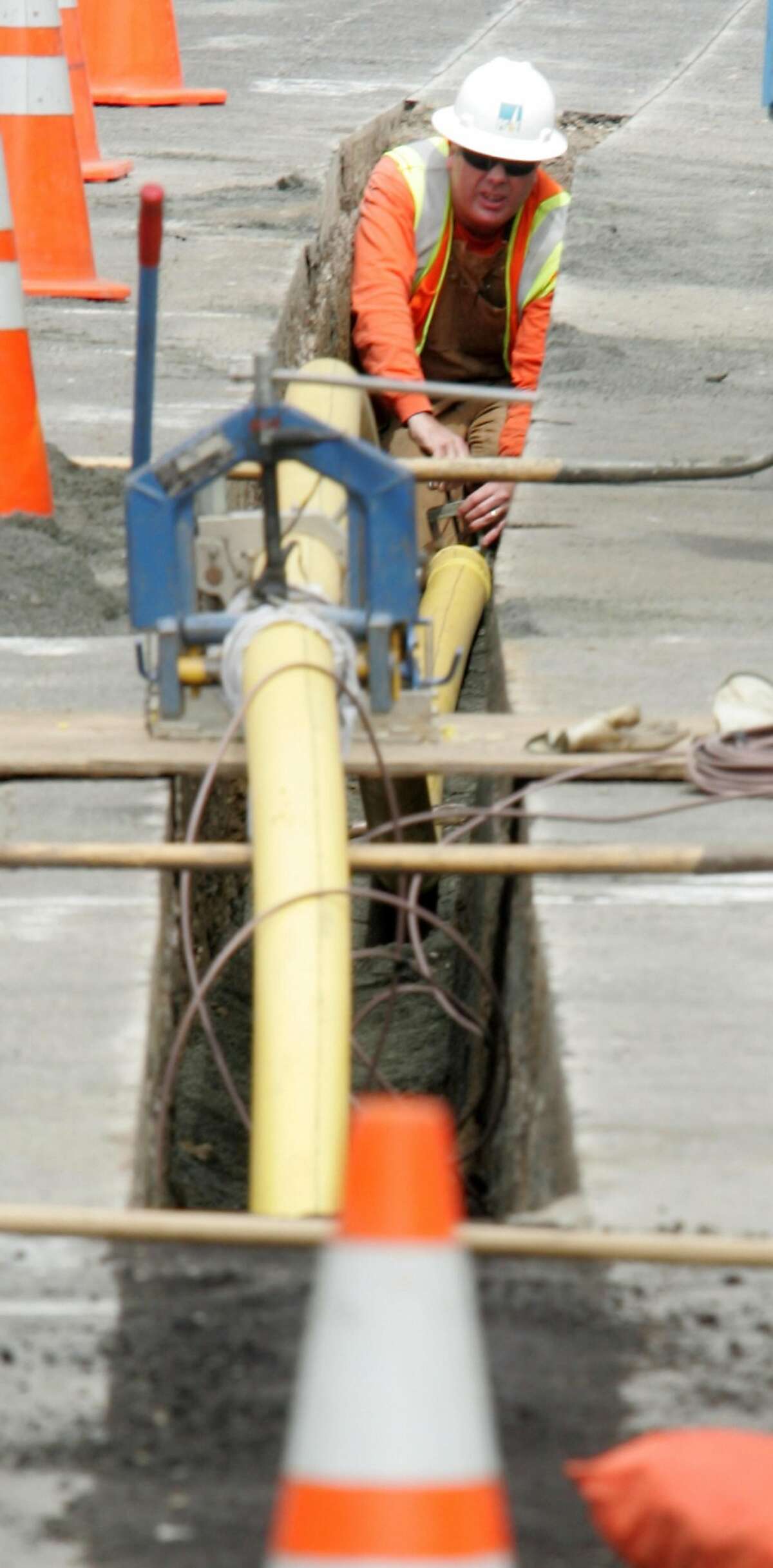 A PG&E worker lays a distribution gas line on Glenview Dr. in San Bruno on Friday near the site of last year's blast.