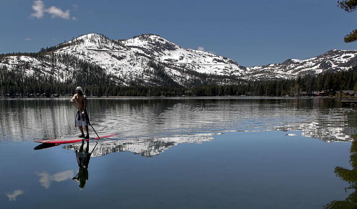 Mitch DeAngelis of Tahoe Donner mixes summer and winter as he paddles Donner Lake, Ca., on Tuesday June 7, 2011. Snow depth monitoring in nearby Soda Springs shows that is is the deepest snow at this date in the high elevations since records were begun in 1868 by the folks that built the Transcontinental Railroad.