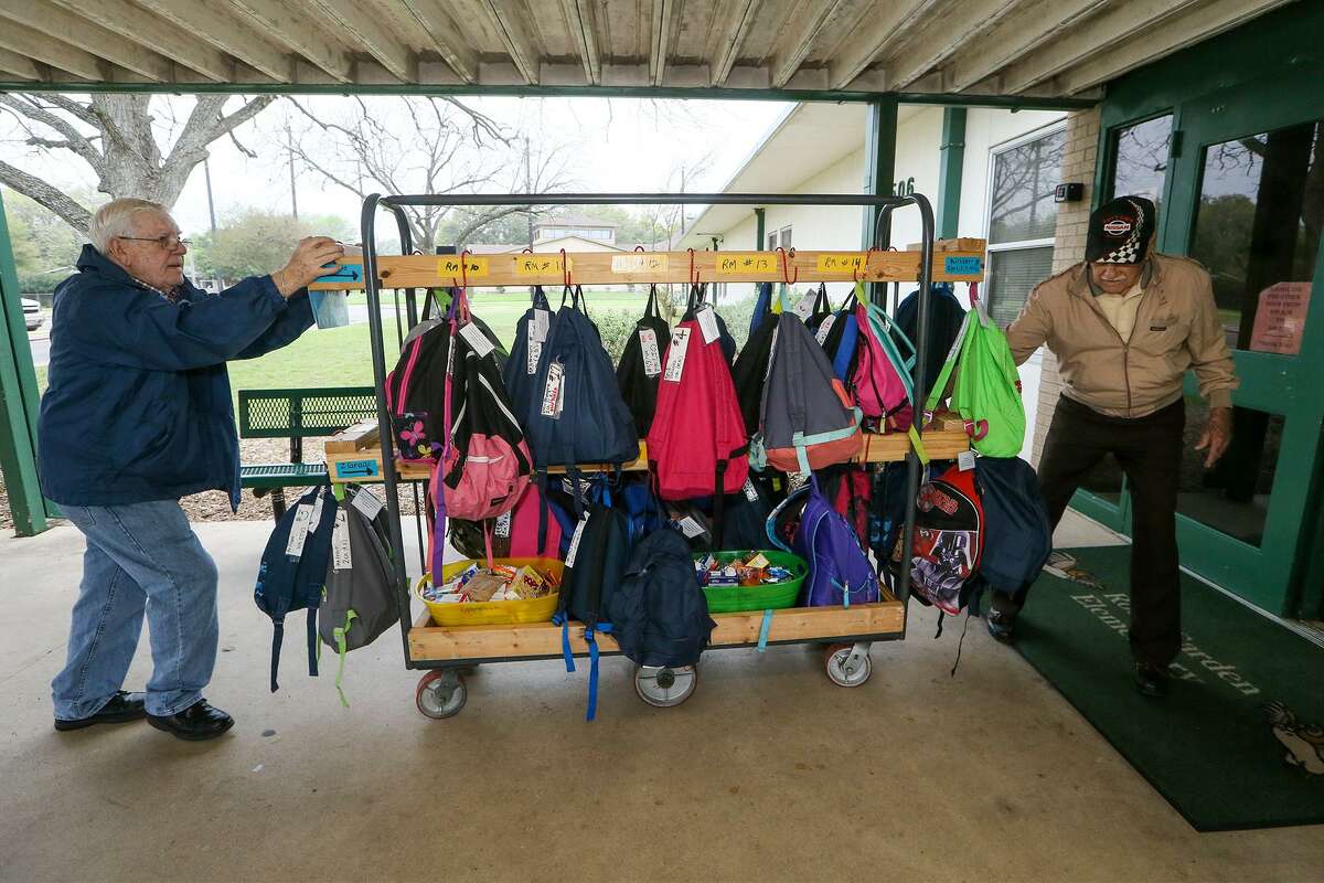 Jim Lloyd (left) and George Atkinson take a transport cart loaded with backpacks from Universal City United Methodist Church into the adjacent Rose Garden Elementary School for distribution to students under "Operation Backpack," a program originated by the church working with Communites in Schools, on Thursday, March 9, 2017.