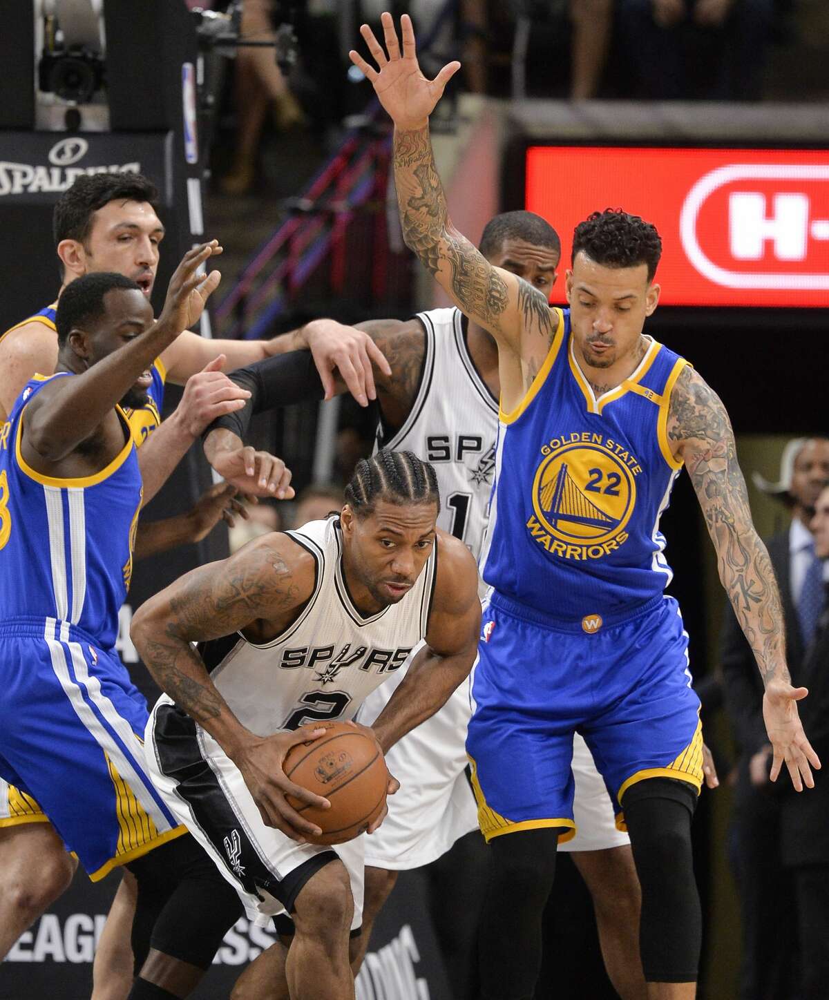 San Antonio Spurs forward Kawhi Leonard (2) looks to pass as he is defended by Golden State Warriors' Matt Barnes (22) and Draymond Green, left, during the first half of an NBA basketball game, Wednesday, March 29, 2017, in San Antonio. (AP Photo/Darren Abate)
