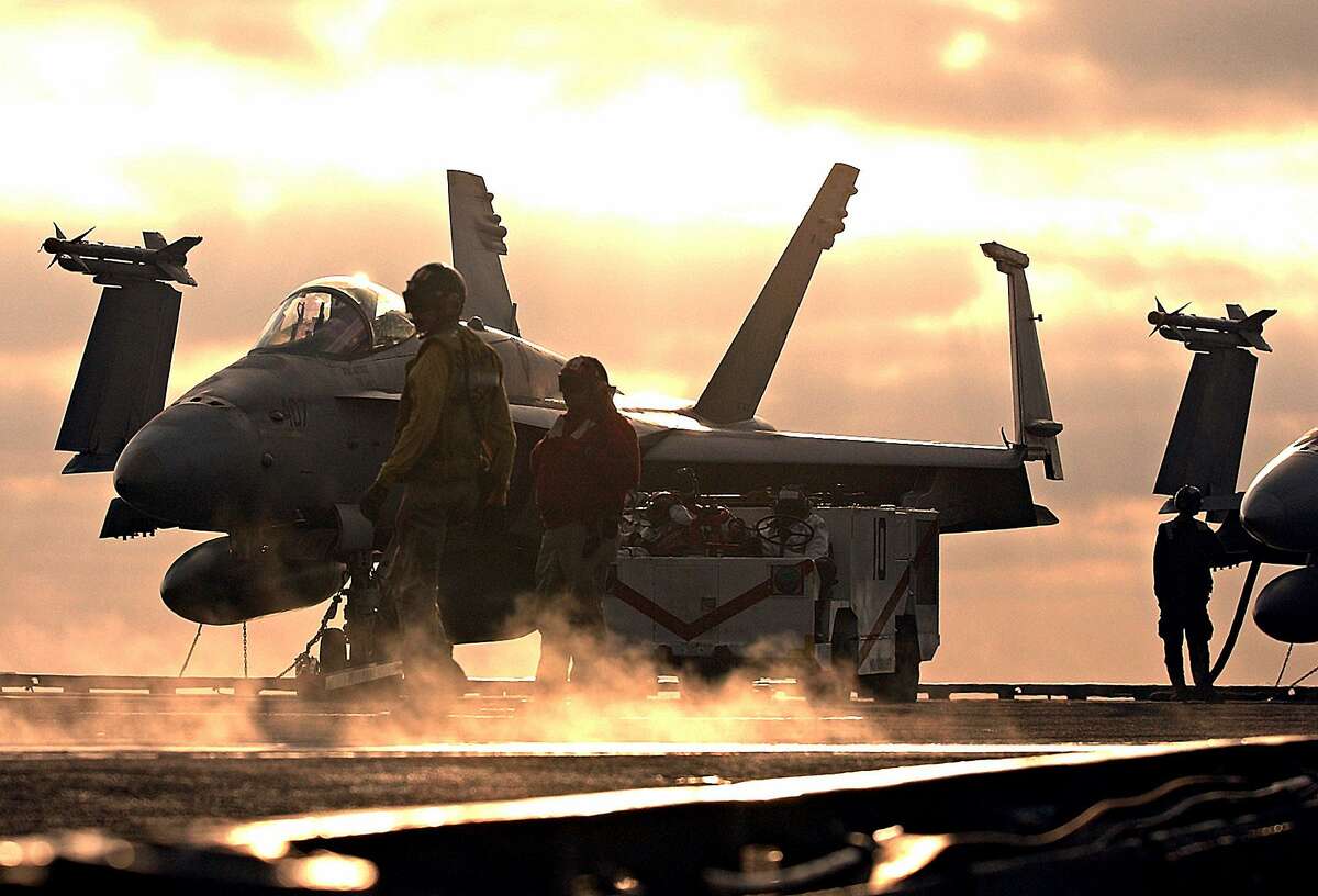 Flight deck crew on the USS Constellation prepare two F/A-18 Hornets for launch as a smoke trail for from another plane is left on the deck Monday, Oct. 28, 2002, during training exercises in the waters off of Southern California. The USS Constellation and its battle group will leave San Diego later this week for a six-month Persian Gulf deployment. (AP Photo/Denis Poroy)