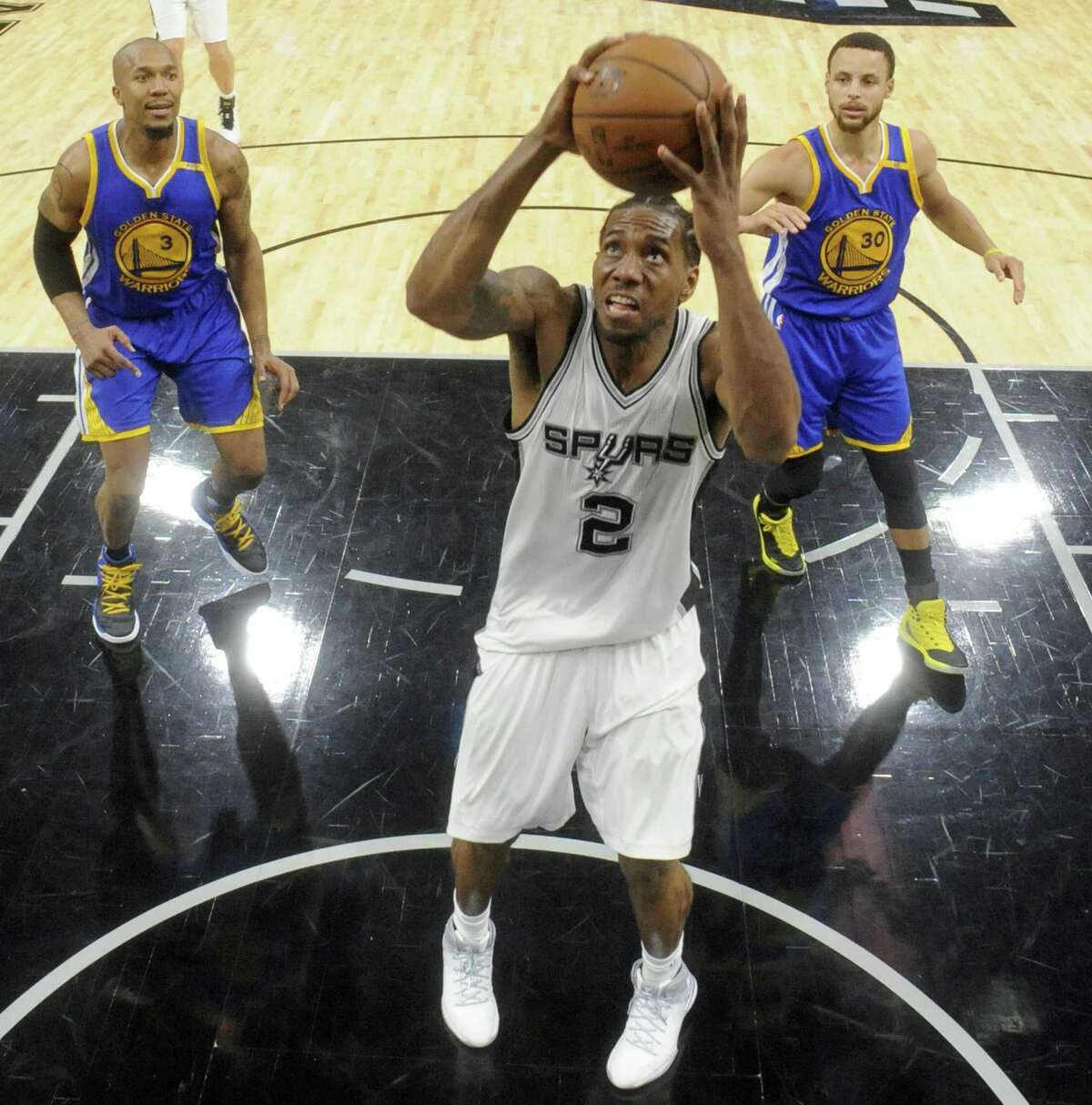 Spurs’ Kawhi Leonard shoots between the Golden State Warriors’ David West (left) and Stephen Curry on March 29, 2017 at the AT&T Center. The Warriors won 110-98.