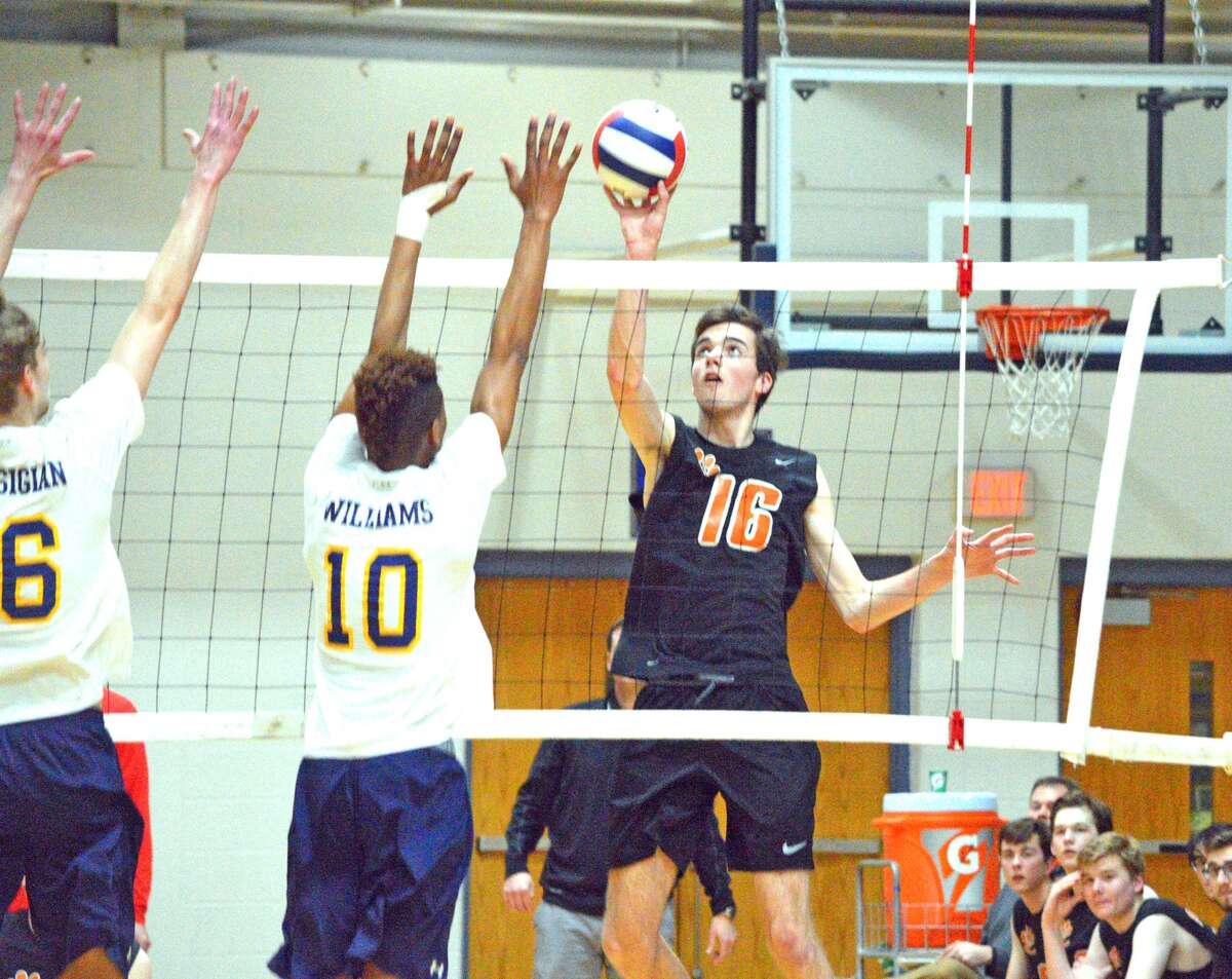 Edwardsville senior Jack Grimm, right, attempts a kill during the first game of Thursday’s Southwestern Conference match at O’Fallon.