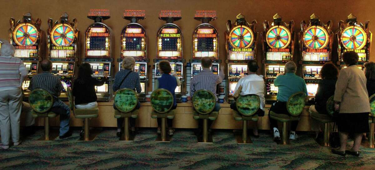 Gamblers huddle around a row of slot machines at Mohegan Sun Casino