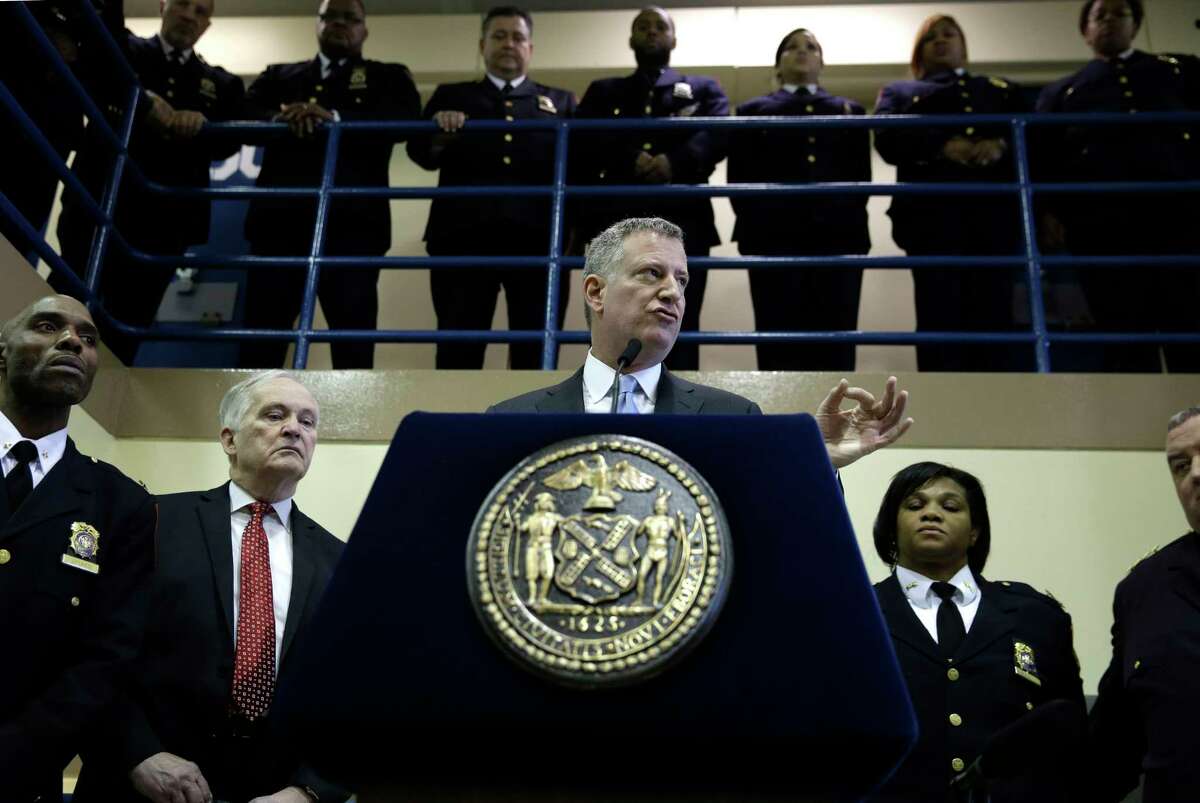 FILE - In this March 12, 2015 file photo, surrounded by corrections officers, New York City Mayor Bill de Blasio holds a news conference on Rikers Island in New York. The mayor announced Friday, March 31, 2017, that he's developing a plan to shut down the massive jail within 10 years.(AP Photo/Seth Wenig, File) ORG XMIT: NYR102