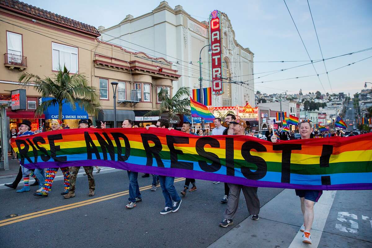 People holding a wide rainbow flag that reads "Rise and Resist!" during a march and memorial in the Castro for Gilbert Baker on Friday, March 31, 2017, in San Francisco, Calif. 