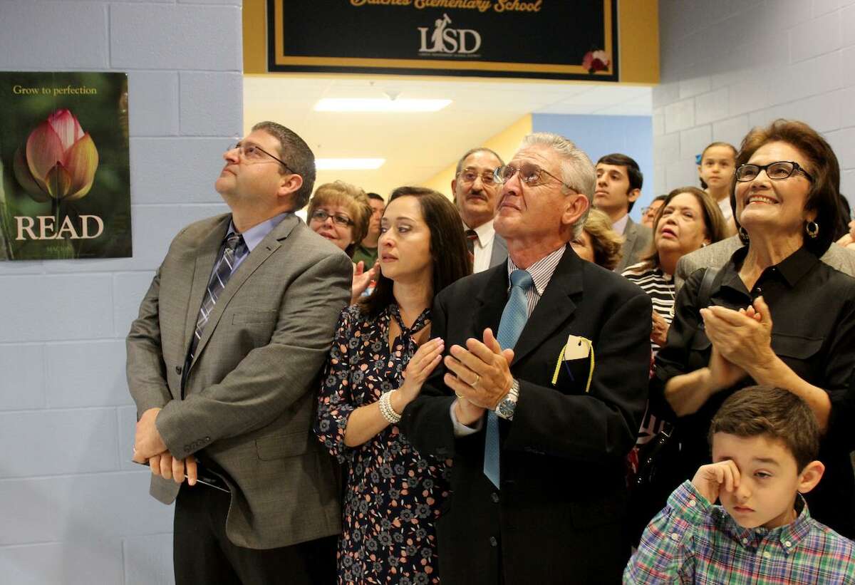 Arnaldo, Claudia, and Nicola Lanese, along with LISD Board President Cecilia May Moreno watch the unveiling of the portrait and lettering that will grace the front of the library.