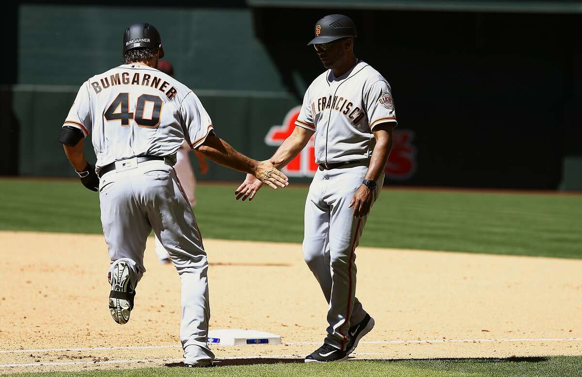 San Francisco Giants' Madison Bumgarner (40) celebrates his home run against the Arizona Diamondbacks with first base coach Jose Alguacil, right, during the fifth inning of an opening day baseball game Sunday, April 2, 2017, in Phoenix. (AP Photo/Ross D. Franklin)