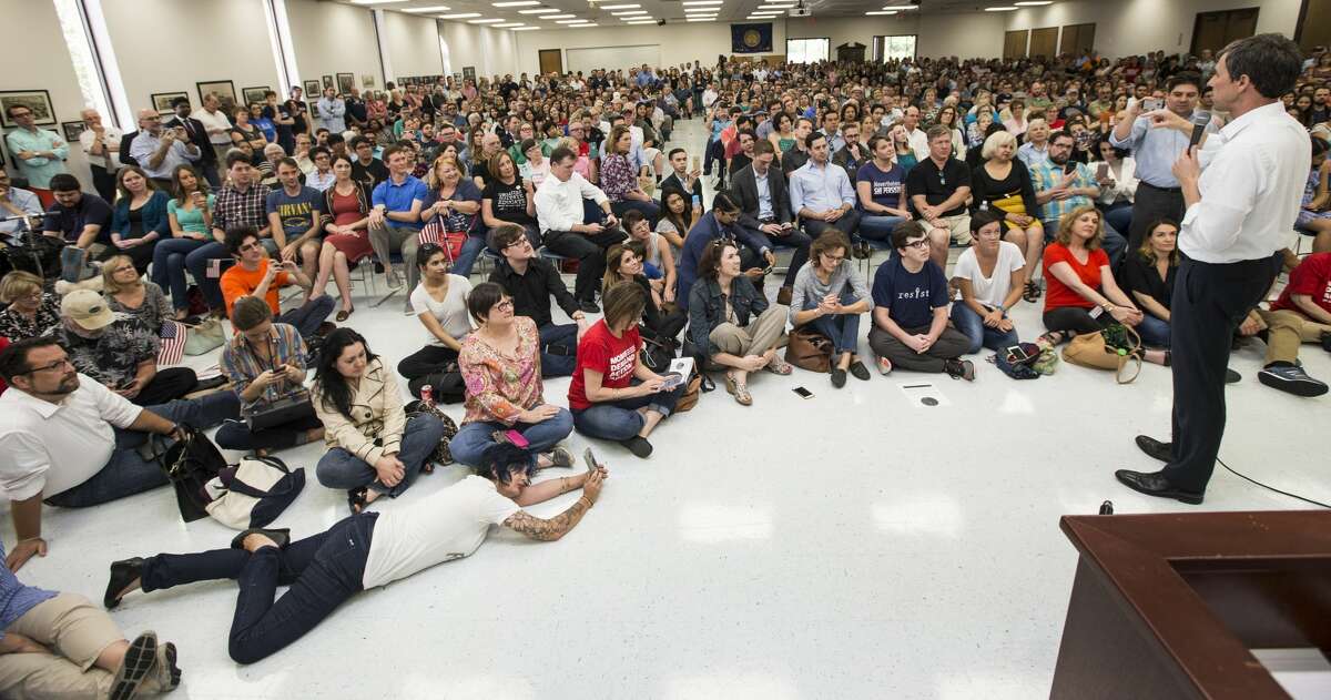 A woman lies on the floor using her phone to capture a speech by Rep. Beto O'Rourke, D-Texas, during an April campaign stop in Houston. ( Brett Coomer / Houston Chronicle )