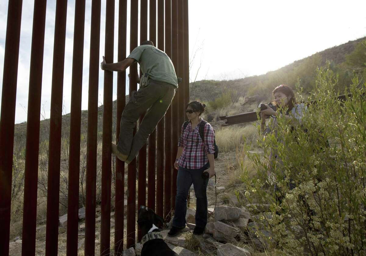 Tim Foley shows how to climb a section of the border wall separating Mexico and the United States near where it ends as journalists Chitose Nakagawa (right) and Marcie Mieko Kagawa look on in Sasabe, Ariz., in this 2016 photo. Bids for the first border wall design contracts are due today.
