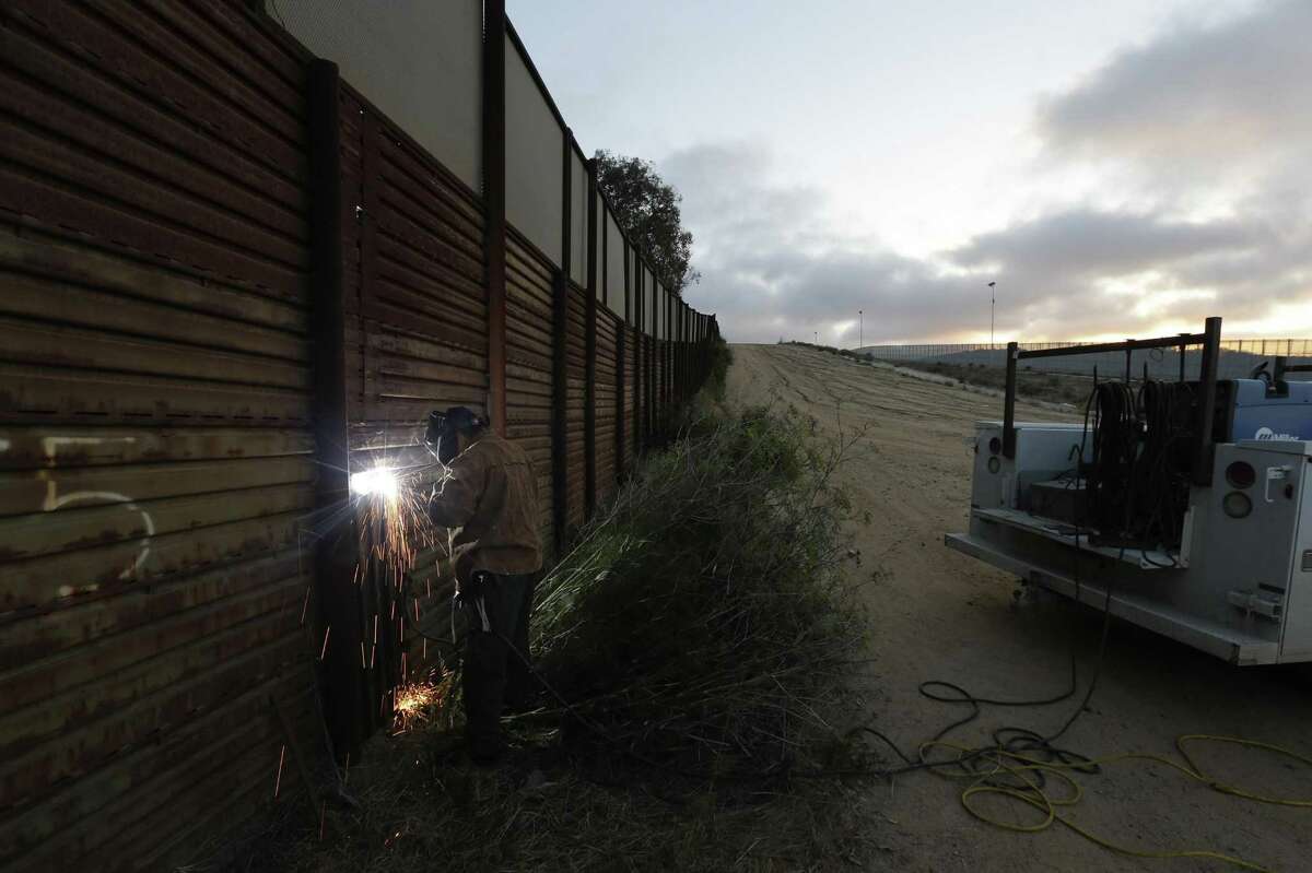 A U.S. Border Patrol agent working with a border wall repair crew welds a section of steel over a hole cut in the border wall in San Diego. One potential bidder on President Donald Trump’s border wall with Mexico wanted to know if the government would help if its workers came under “hostile attack.”