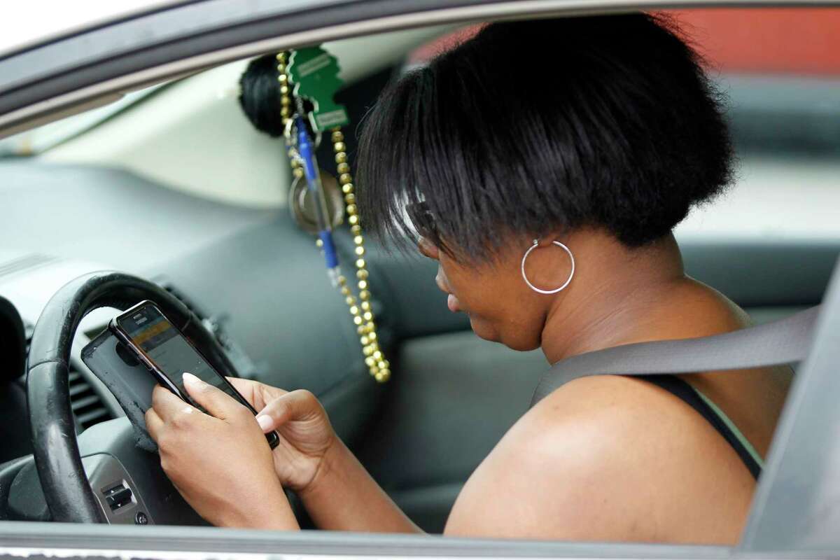 A woman texts as she drives along Westheimer near The Galleria in Houston on March 9.
