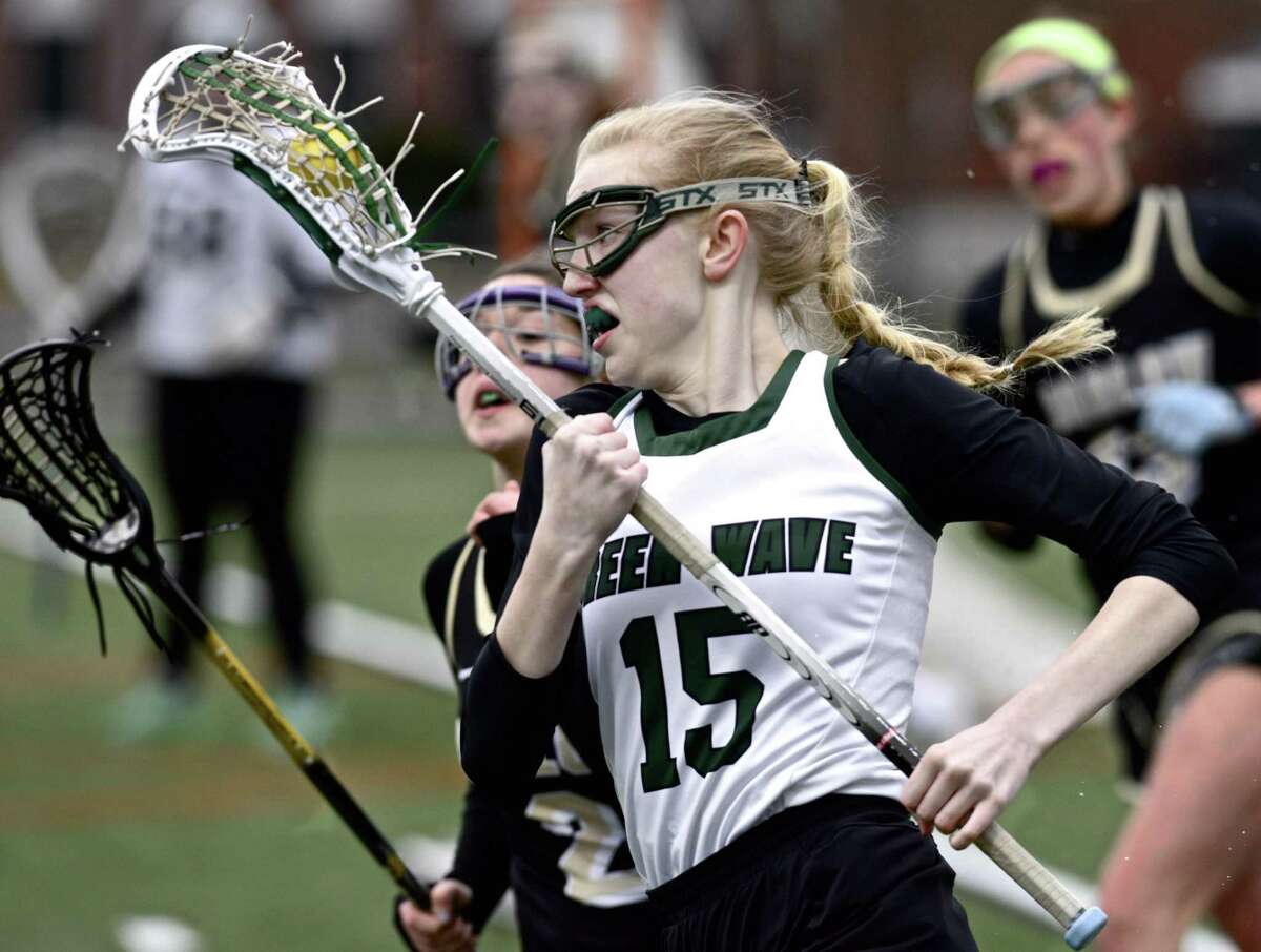 New Milford’s Taylor Kersten (15) goes by Barlow’s Elisabeth Eastus during their girls lacrosse game Tuesday at New Milford High School. The Green Wave won 11-10.