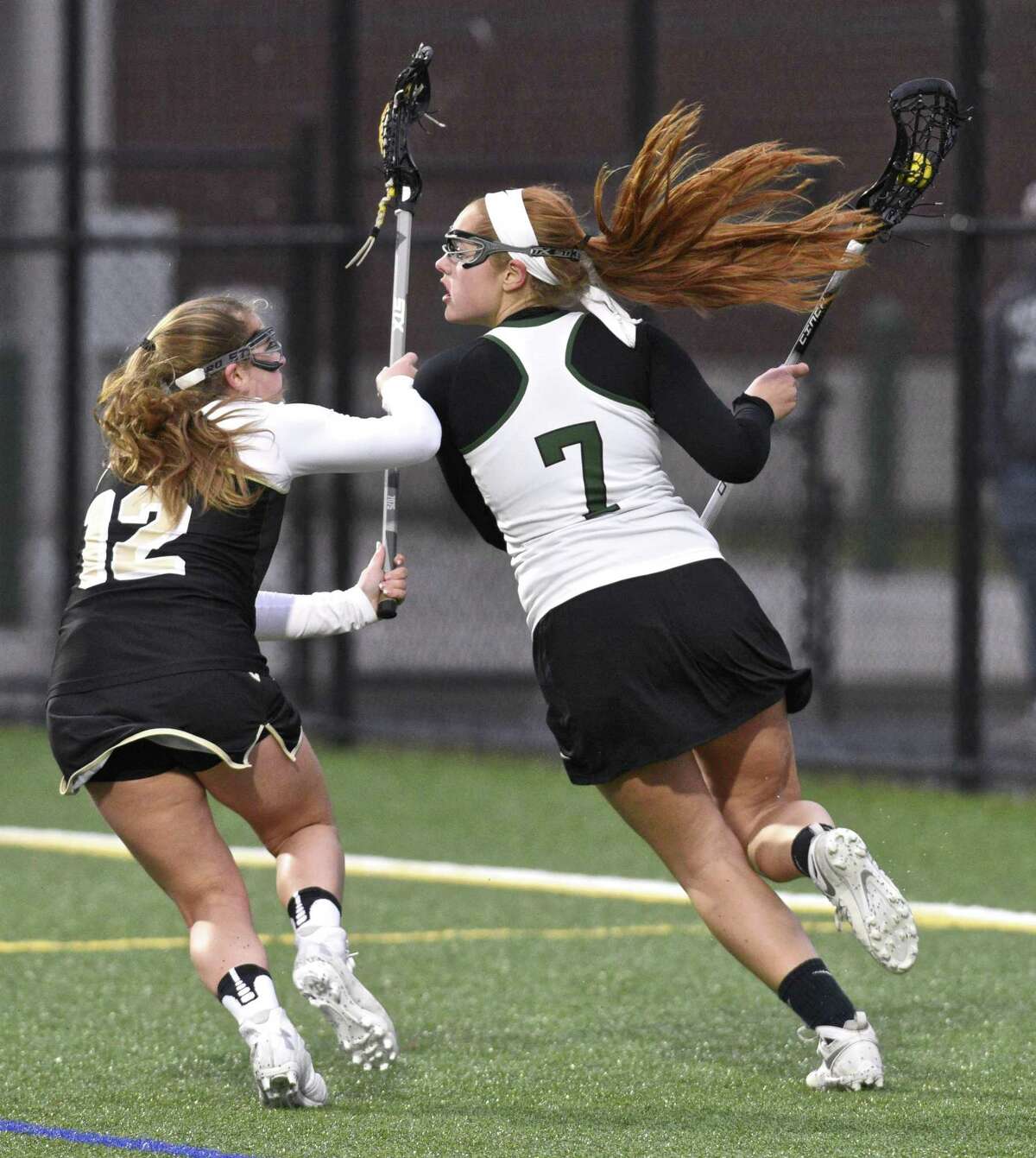 New Milford's Grace O'Donnell (7) is defended by Barlow's Sydney Lockwood (12) behind Barlow's goal in the girls lacrosse game between Joel Barlow and New Milford high schools, on Tuesday April 4, 2017, at New Milford High School, New Milford, Conn.