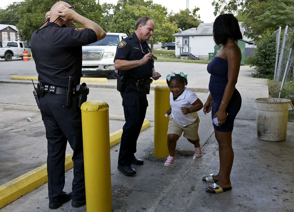 SAPD Patrol Officers David Nouhan, left, and Michael Trainor talk with E'Dheja Wolford as Janiyah Greenwood, 4, runs towards the door of a convenience store as the officers patrol the area targeted by the Byrne Grant on Walters Street on Sept. 15, 2016.