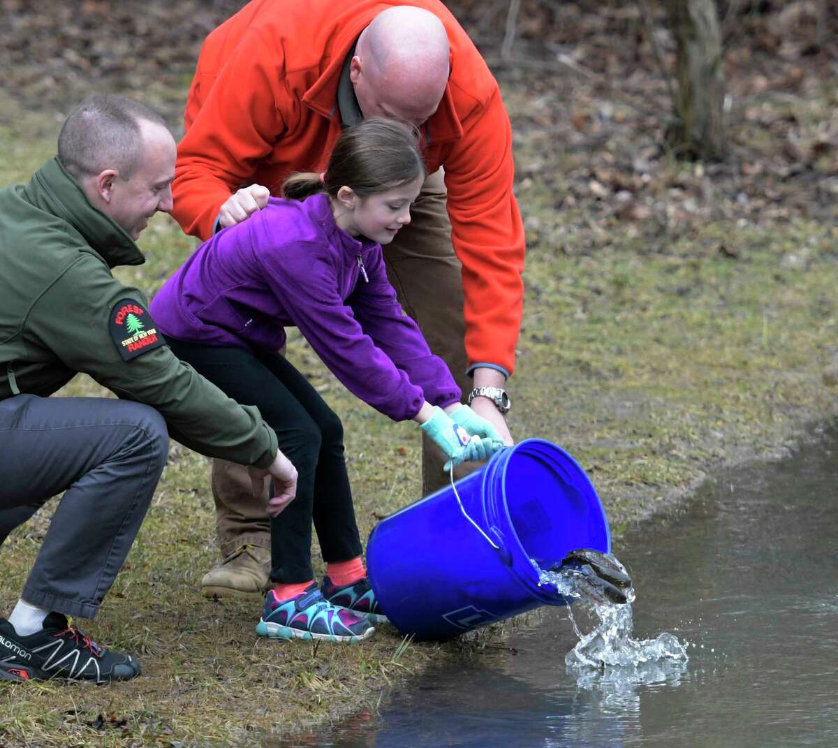 With an assist from the NYS ENCON Commissioner Basil Segos, left and teacher Tim Mattison a second grade Voorheesville Elementary School student releases young fish in to the Vly Creek Wednesday April 5, 2017 in Voorheesville, N. Y. Skip Dickstein/Times Union)