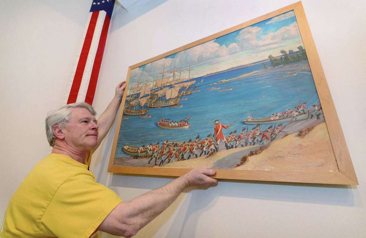 Ed Hynes hangs a depiction of the British landing at Compo Beach for the exhibit at the Westport Historical Society.