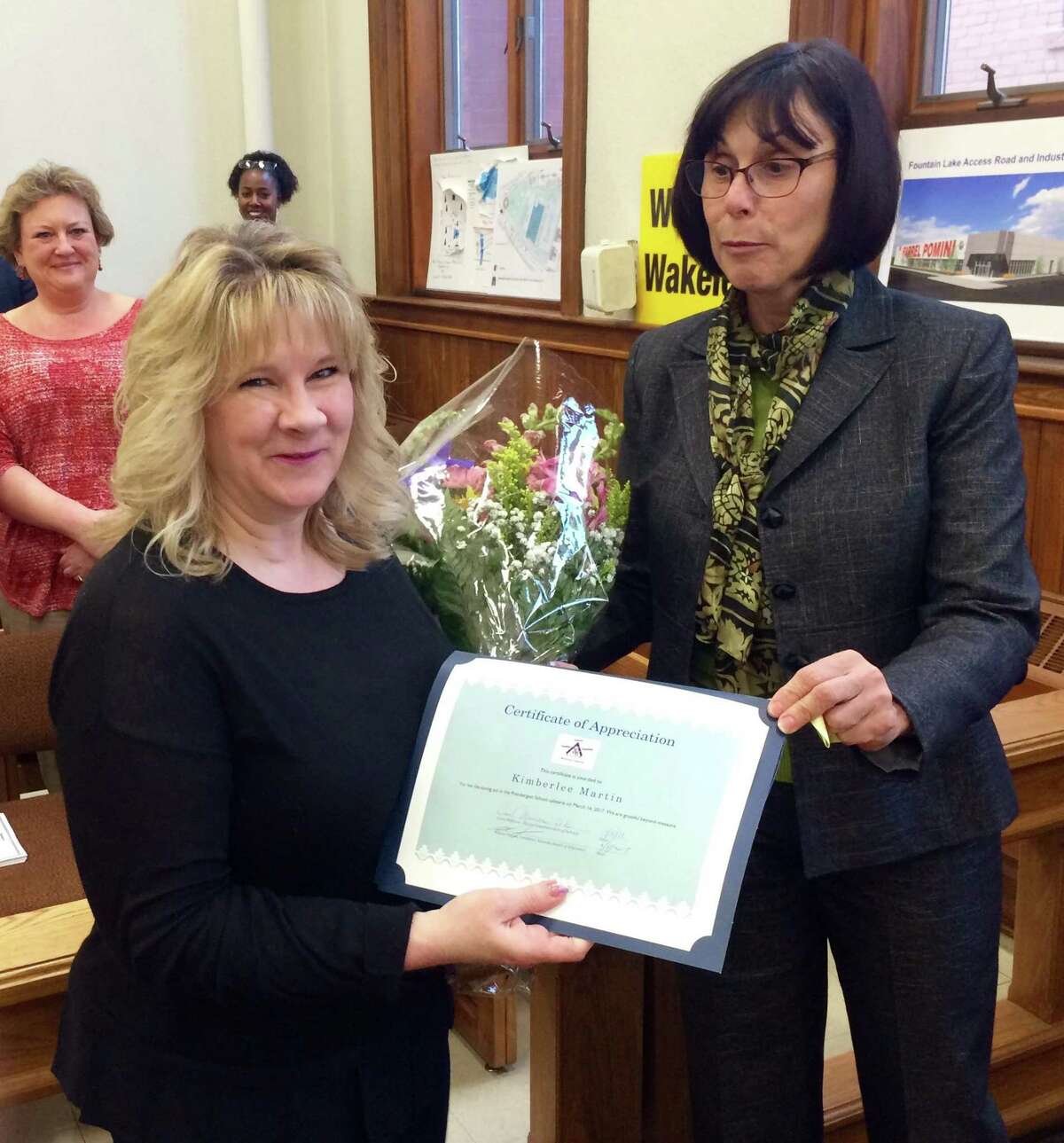 Ansonia Superintendent of Schools Carol Merlone presents a bouquet and a certificate of appreciation on April 5 to Kim Martin, a Prendergast School kindergarten teacher’s aide whose actions saved a six-year-old student from choking on food March 16.
