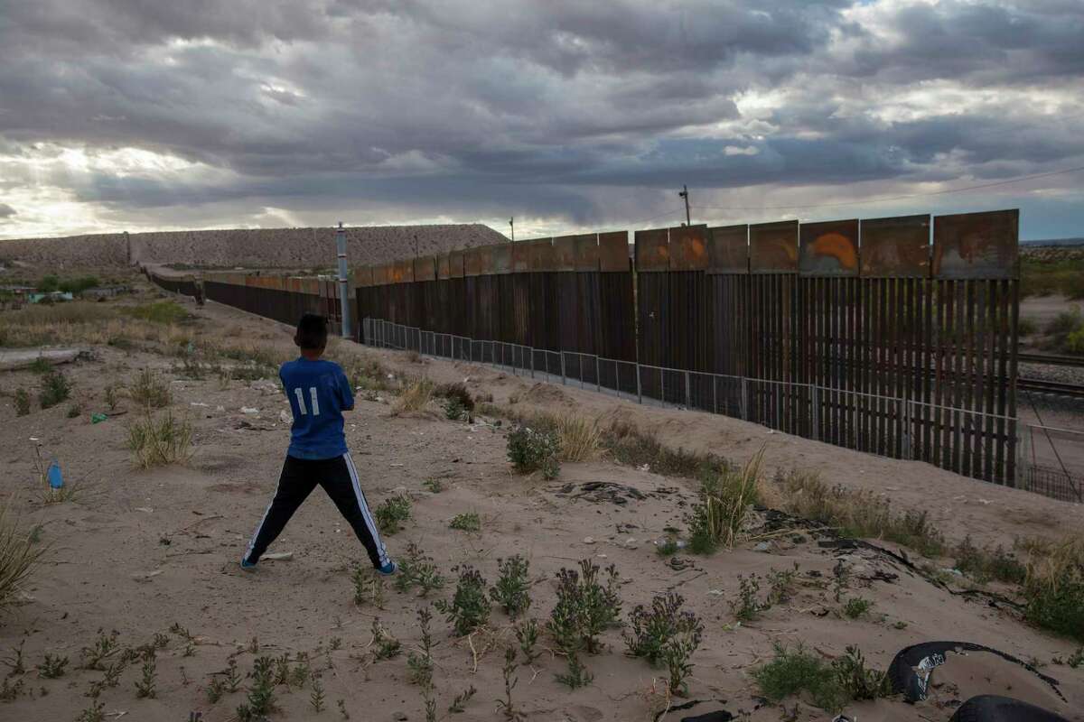 FILE - In this March 29, 2017, file photo, a youth looks at a new, taller fence being built along U.S.-Mexico border, replacing the shorter, gray metal fence in front of it, in the Anapra neighborhood of Ciudad Juarez, Mexico, across the border from Sunland Park, New Mexico. Most Americans oppose funding President Donald Trump's wall along the U.S.-Mexico border. ThatÂ?’s according to a poll released Thursday by The Associated Press-NORC Center for Public Affairs Research. (AP Photo/Rodrigo Abd, File)