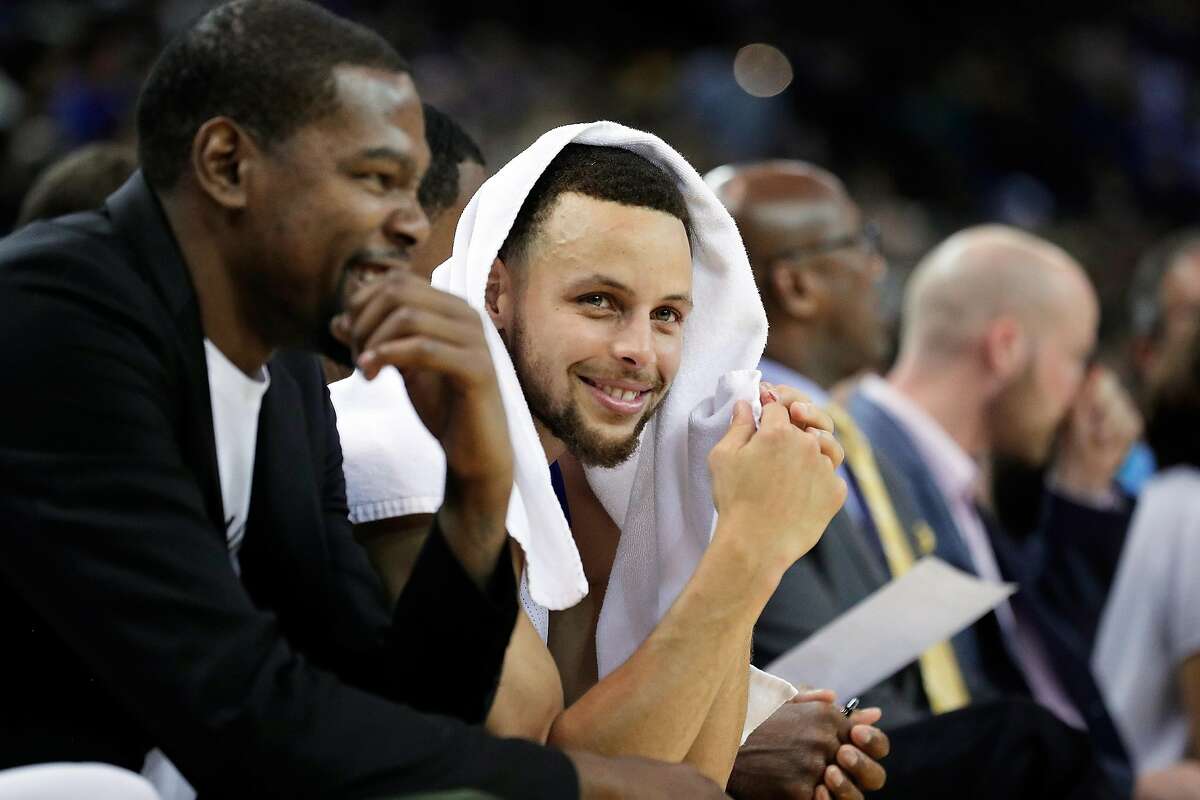 Stephen Curry (30) smiles on the bench with Kevin Durant (35) as the Golden State Warriors played the Minnesota Timberwolves at Oracle Arena in Oakland, Calif., on Tuesday, April 4, 2017.