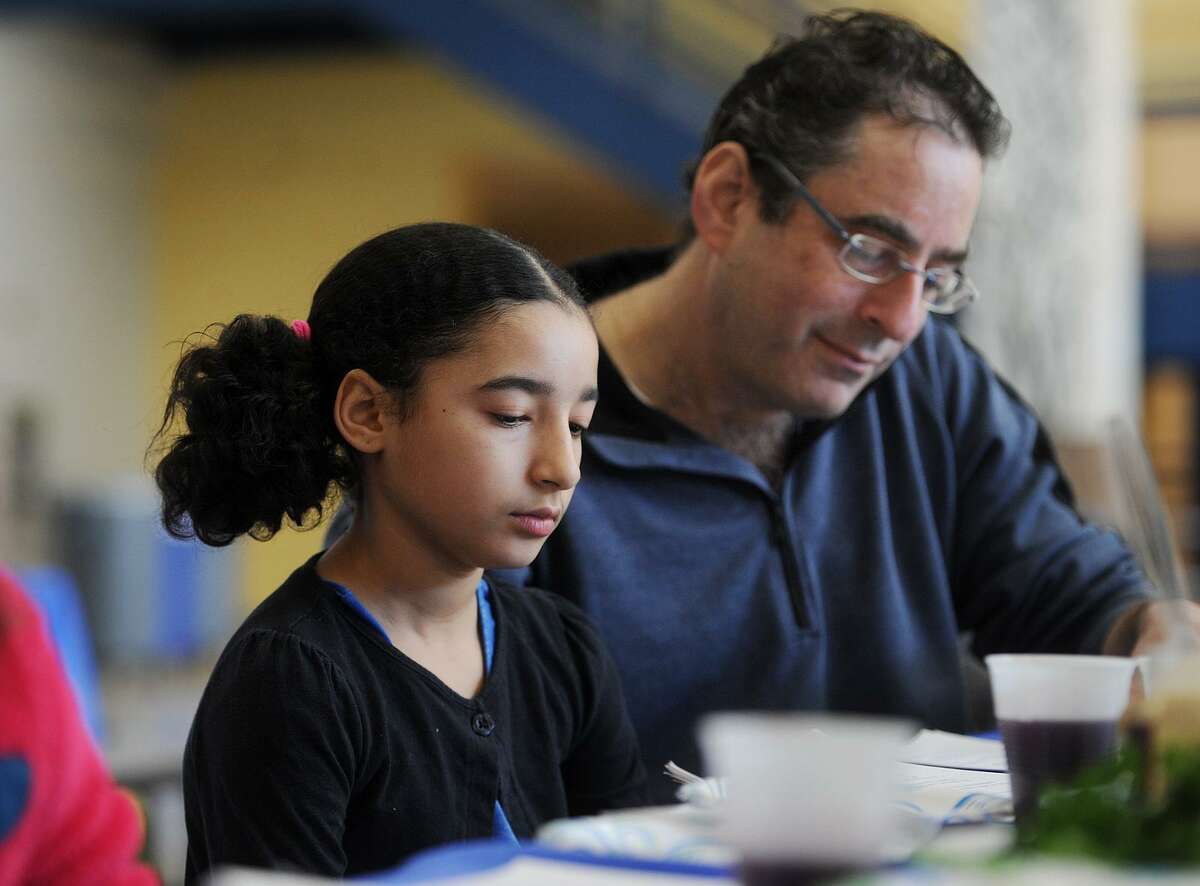Anya Lowenstein, 9, and her father Mike Lowenstein, of Fairfield, participate in The Congregation of Humanistic Judaism Sunday school model Passover Seder at Bedford Middle School in Westport, Conn. on Sunday, April 2, 2017. Part of the mission of the congregation, founded in 1967, is to celebrate Jewish holidays and traditions in non-theistic ways.