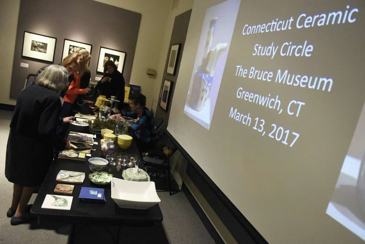 Attendees look over ceramic pieces at the Bruce Museum before a lecture hosted by the Connecticut Ceramics Study Circle in March.