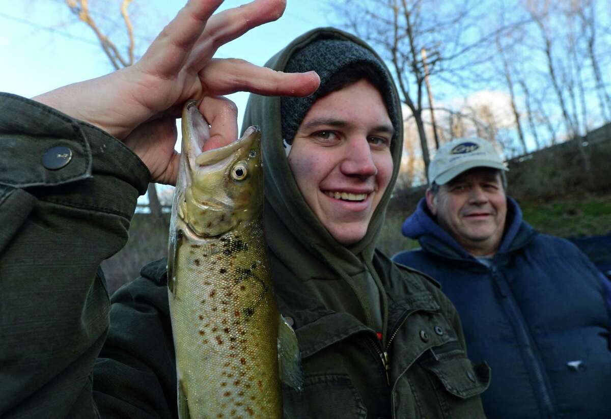 Norwalk residents Anthony Russo and his father Bob Russo display a trout they caught while fishing on the Norwalk River during opening day Saturday, April 8, 2017, in Wilton, Conn.