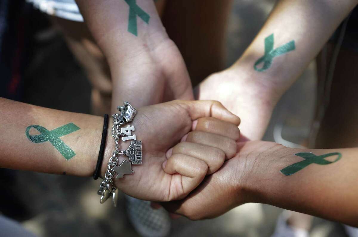 Four friends, all students at UTSA, compare their temporary tattoos of a teal ribbon during the recent National Call to Action Day, aimed at raising awareness about sexual assault at colleges.